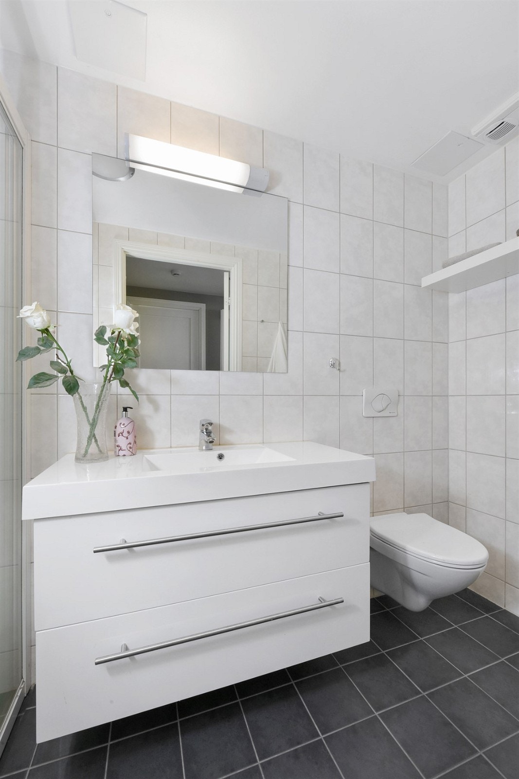 Det andre badet har speil med overbelysning, heldekkende servant på moderne skuffemøblement, hylle og veggmontert toalett. Galleribilde