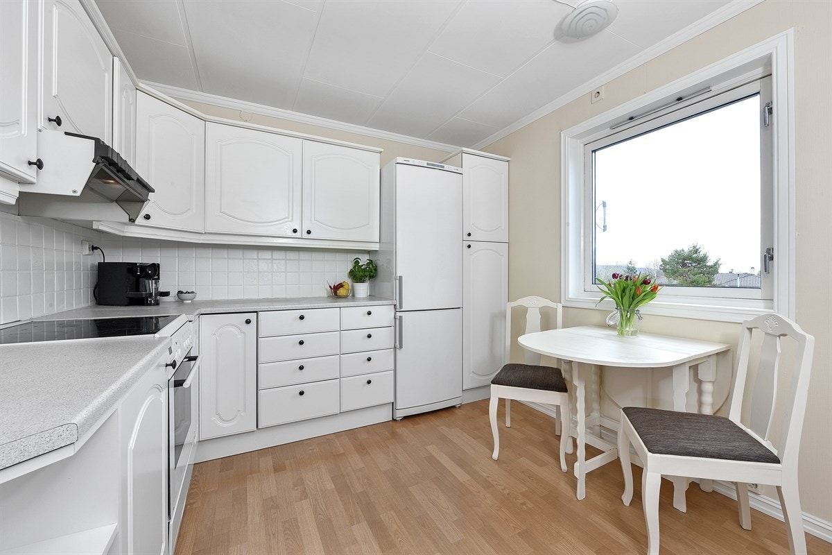 Over benken som er laminert og har dobbel vaskekum, er det lyse fliser og benkebelysning. Galleribilde