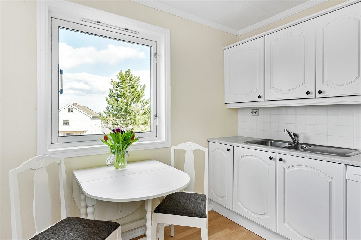 Rommet har lyse overflater og mulighet for spiseplass ved vinduet. Galleribilde