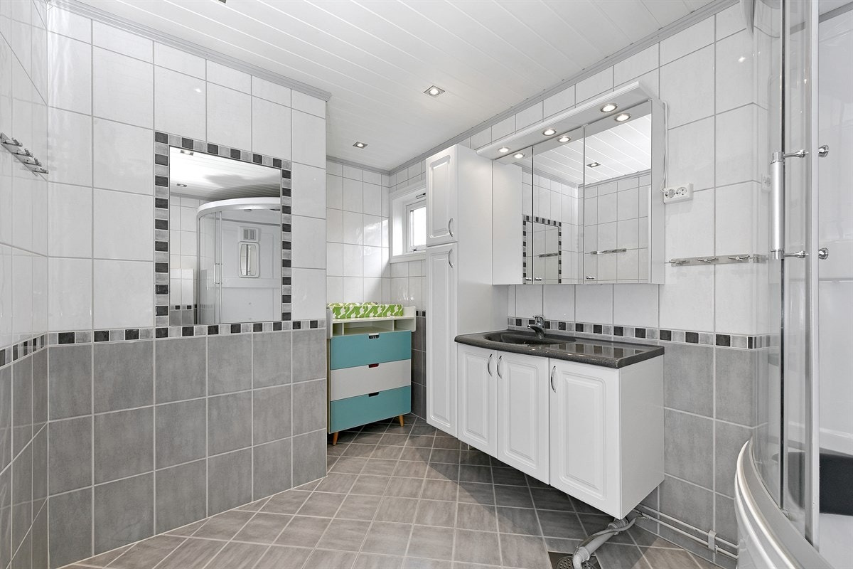 Det ene badet ligger i første etasje og har overflater med fliser i lyst og grått, samt downlights i himling. Galleribilde