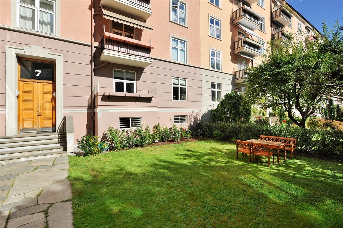 Pent opparbeidet tomt med forhage med gress, busker og skiferbelagt gangvei. Galleribilde