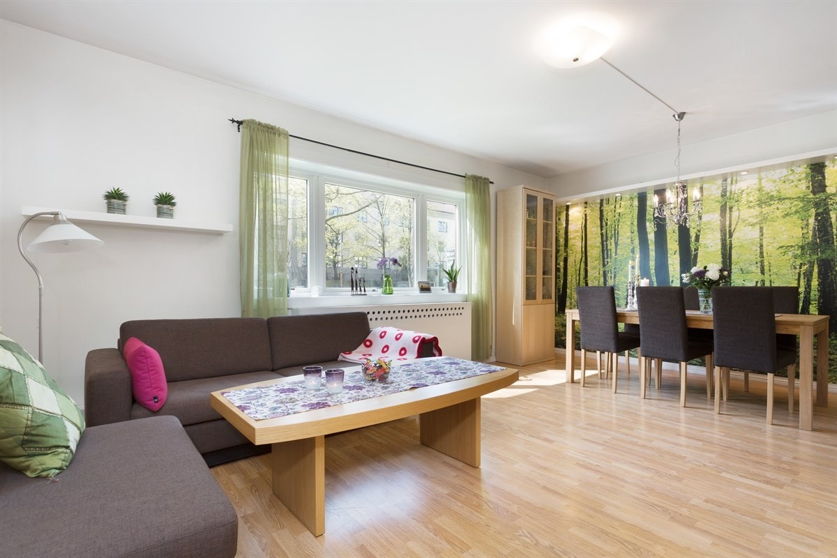 En stor stue med plass til både sofaseksjon og spisebord. Mye naturlig lys gjennom store vindusflater. Galleribilde