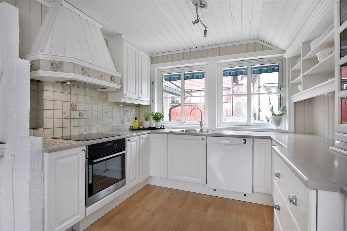 Kjøkkeninnredningen har hvitmalte, profilerte fronter, vitrineskap og åpne hyller, samt gode arbeidsflater. Galleribilde