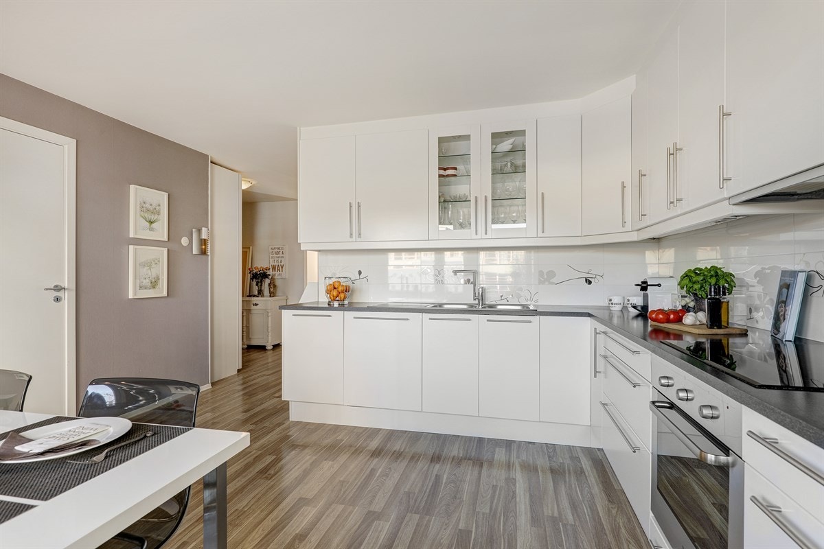 Kjøkkeninnredningen er stilren med hvite glatte fronter og laminert benkeplate med nedfelt stålkum. Galleribilde