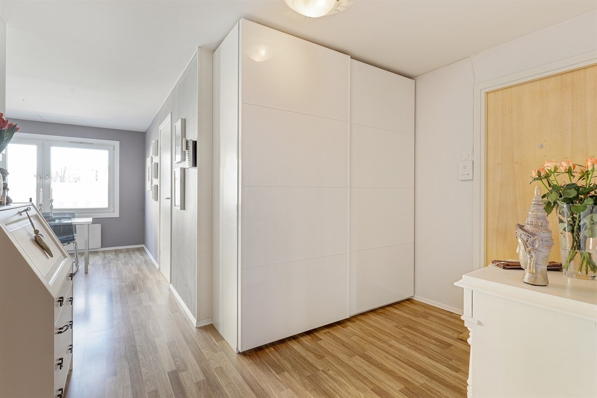 På høyre side i entréen har du en moderne skyvedørsgarderobe, hvor du kan henge deg ytterjakken og sette fra deg skoene, før du går videre inn i boligen. Galleribilde