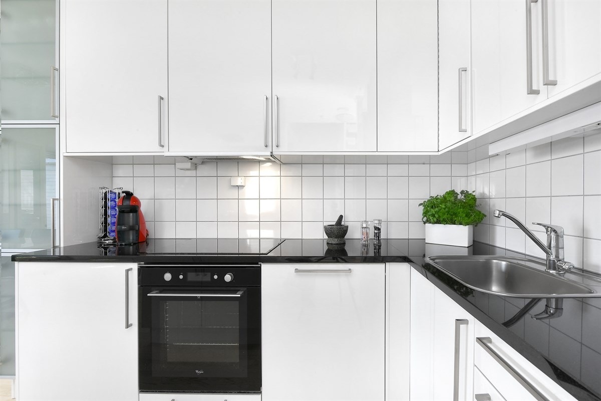 I enden av innredningen er det et høyskap med vitrinedører og en praktisk kjøkkenøy skaper et naturlig skille ut mot stuen. Galleribilde