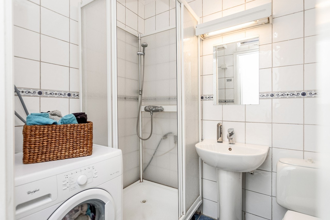 Flislagt bad med dusjkabinett og opplegg til vaskemaskin Galleribilde