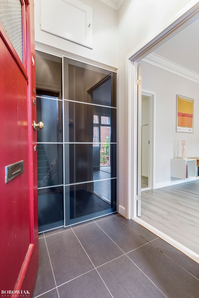 Romslig entrè med tilknyttning til stue. Praktisk gulvflate med mørke fliser. Selve entréen gir gode oppbevaringsmuligheter med en plassbygd skyvedørsgarderobe. Galleribilde