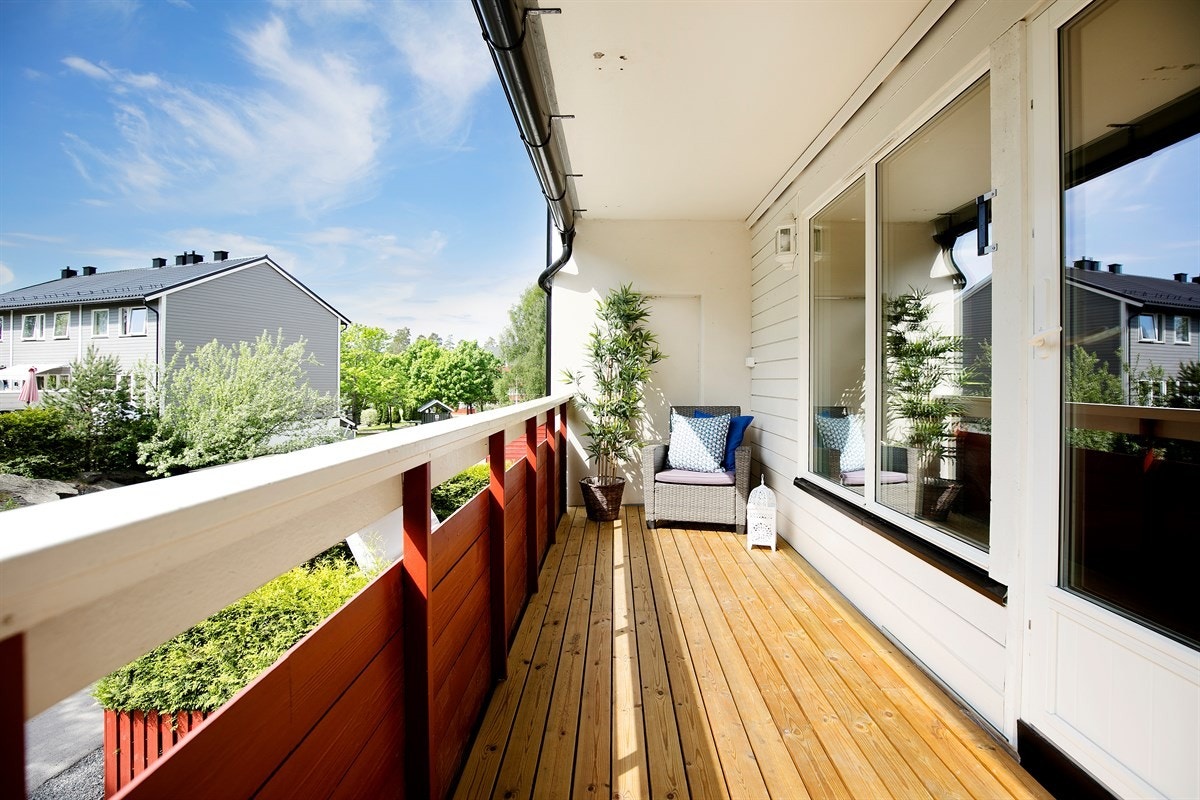 Balkongen har terrassebord på gulv og god plass for utemøblement Galleribilde