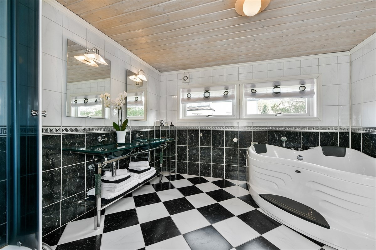 Badet ligger i andre etasje og har fliser på gulv med sjakkmønster og fliser i to farger på veggen. Galleribilde