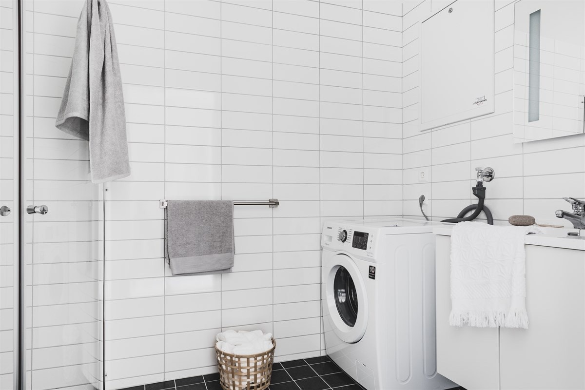 Fra gangen er det dør inn til badet på venstre side. Dette er romslig og stilrent med hvite fliser på vegger og mørkegrå på gulv. Galleribilde