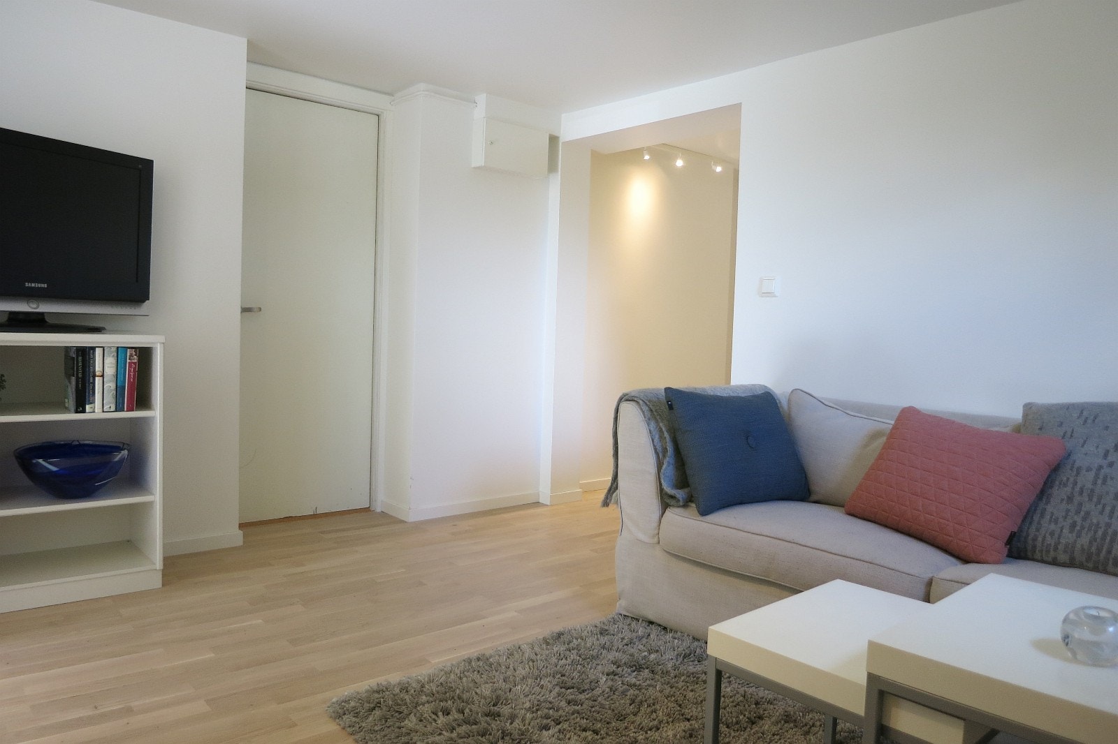 I dag er det en nyere, mørkegrå sofa som står der og et nytt teppe (2024). Ingen bord. Ikke tv. Galleribilde