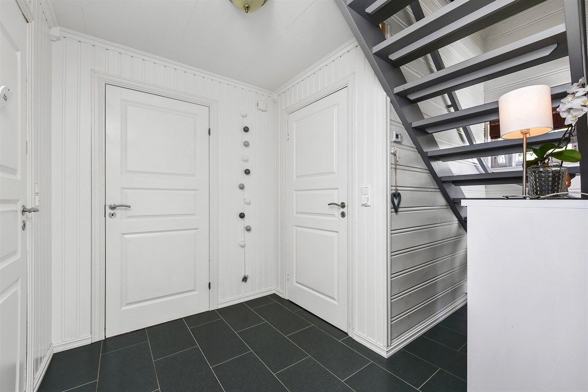 Det er fliser på gulv i gangen mellom stue og entreen. Galleribilde