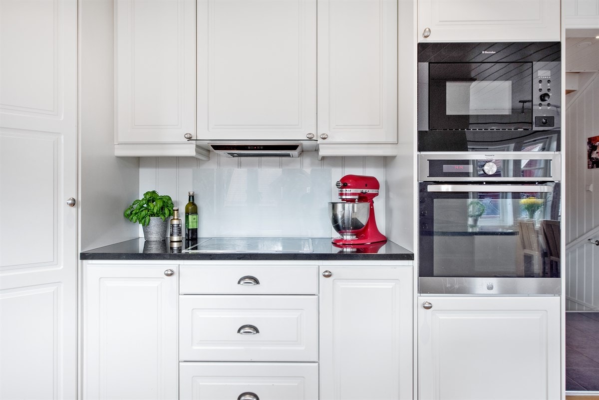 Meget pent kjøkken med hvite glatte fronter og integrerte hvitevarer Galleribilde