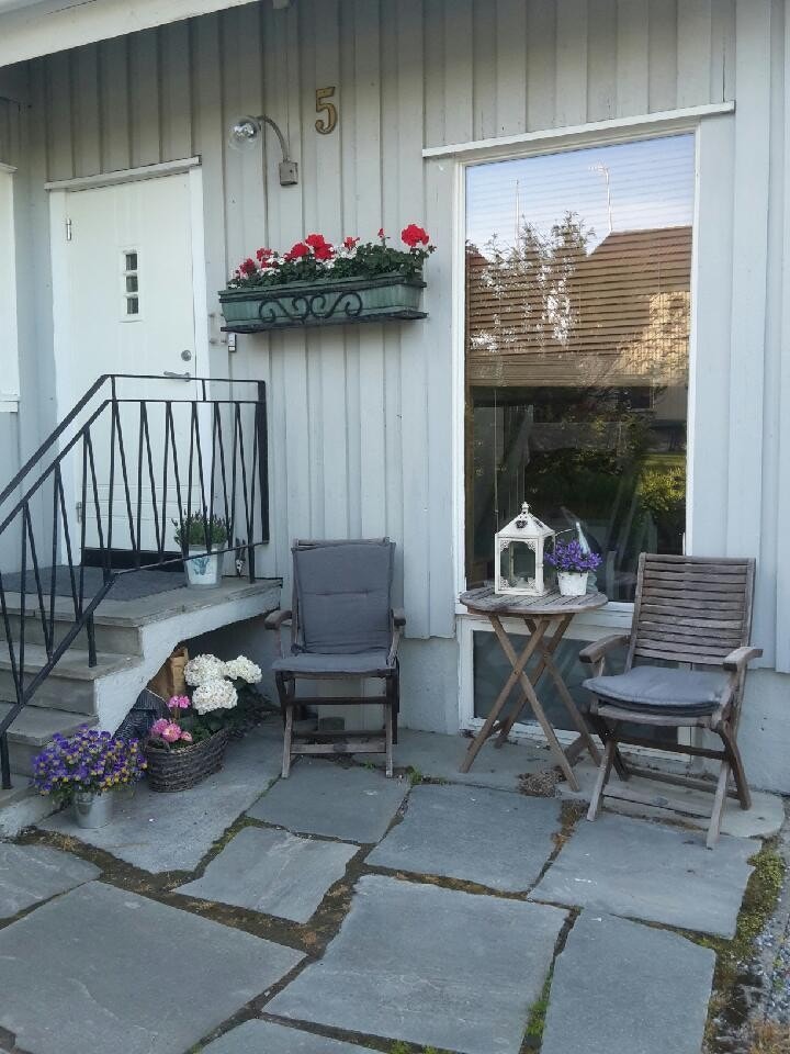 Inngang med en uteplass mot sør. Det er også grønn plen tilgjengelig for en sommerdag Galleribilde