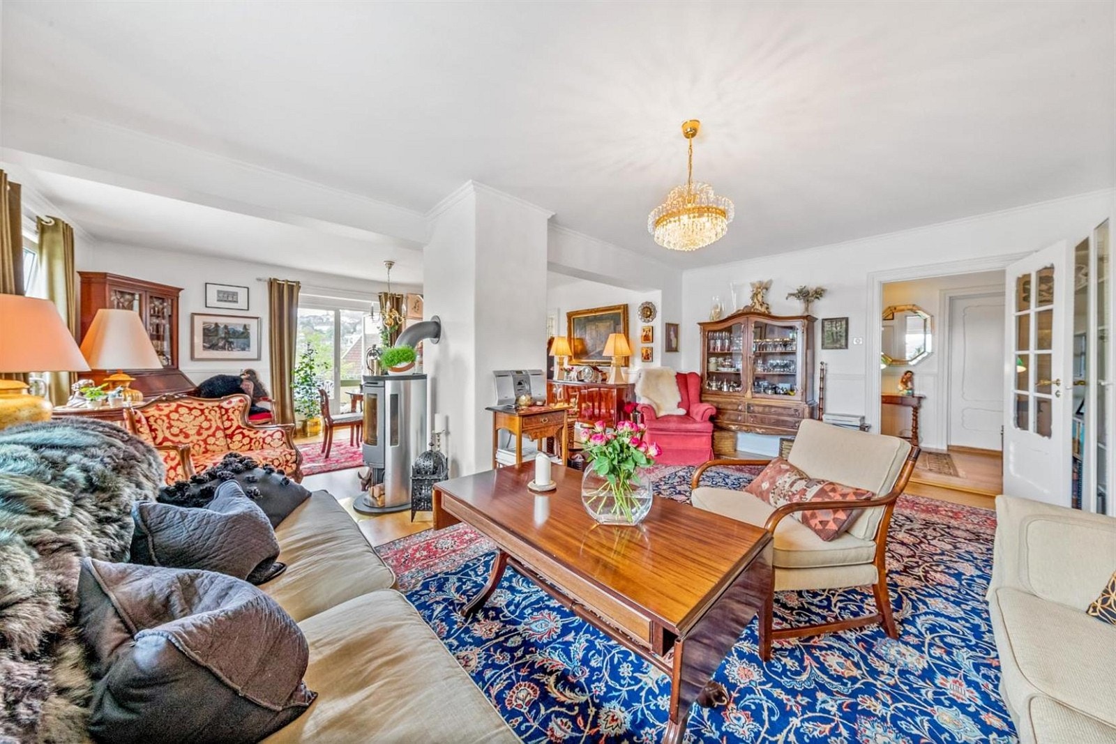 Stor innbydende stue med peisovn, store vindusflater og utgang til balkong. Galleribilde