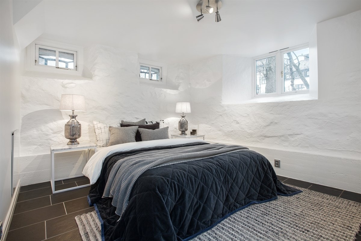 Hovedsoverommet har hvitmalte murvegger, flere vindusløsninger og flislagt gulv med deilig gulvvarme Galleribilde