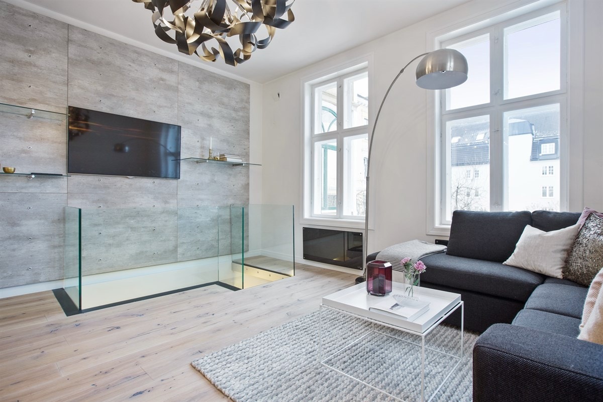 En vegg med funksjonelle plater gir smart oppheng for tv og hylleløsninger, men samtidig en røff kontrast til ellers lysmalte overflater Galleribilde