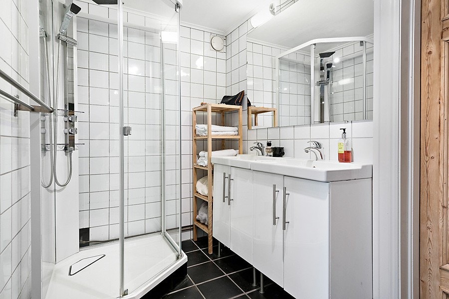 Romslig eldre bad. Badet preges av nøytrale og delikate materialvalg med hvite fliser på vegg og sorte gulvfliser. Galleribilde