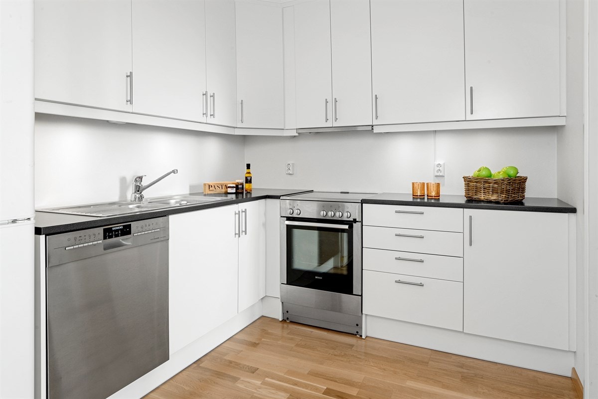 Innredningen har lyse, glatte fronter, laminert benkeplate med dobbel vaskekum, samt nisje for kjøleskap. Galleribilde