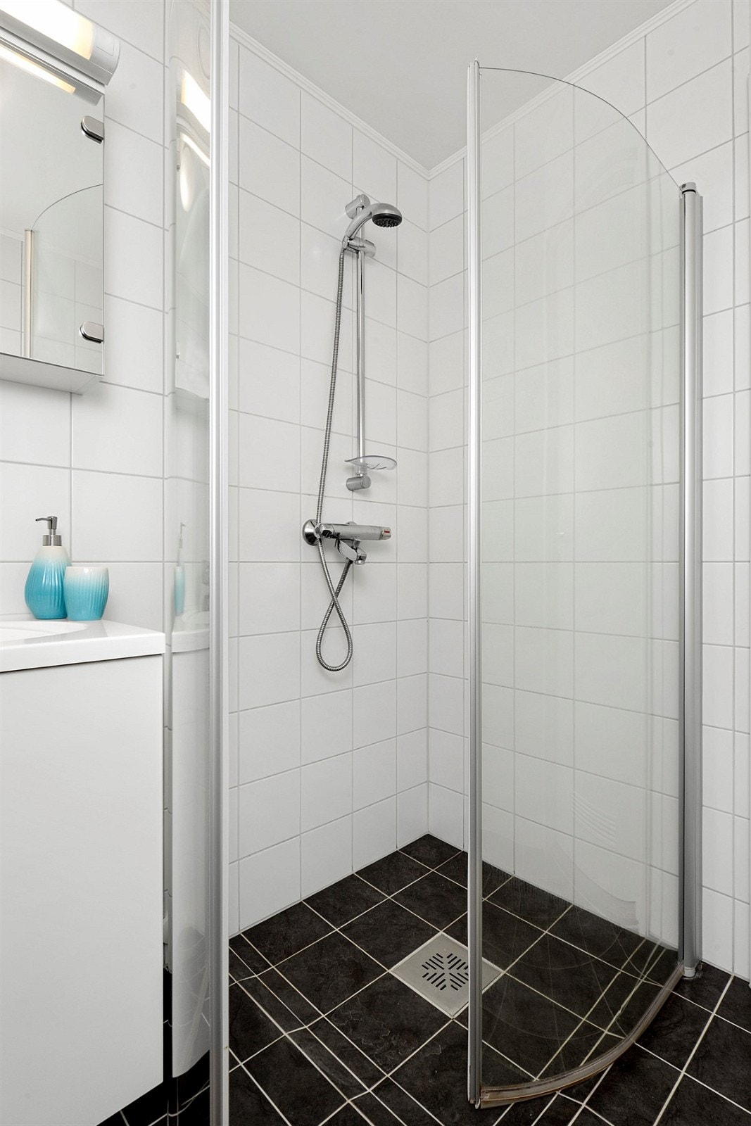 Boligen inneholder et lyst og moderne bad som er utstyrt med mørke fliser på gulv, hvite fliser på vegg, gulvvarme og elektrisk avtrekksvifte. Galleribilde