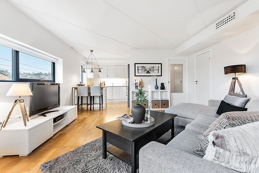 Moderne planløsning med åpen løsning mellom stue mot kjøkken. Store vindusflater på to sider preger stuen og gir fantastisk lys inn i leiligheten. Galleribilde