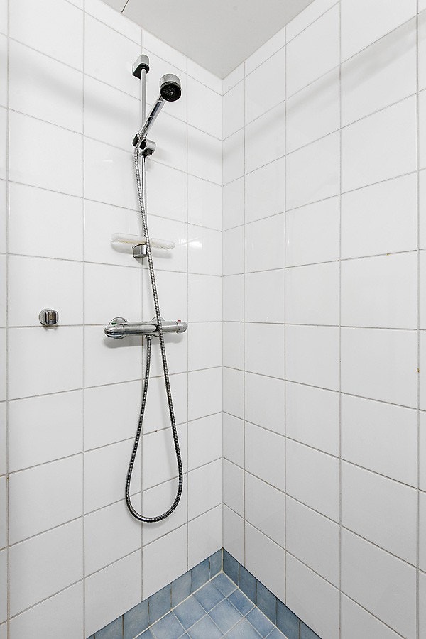 Lyst og pent flislagt bad med varmekabler i gulv og opplegg for både vaskemaskin og tørketrommel. Baderomsinnredning fra byggeår med frittstående toalett, dusjhjørne og servant med underskap . Mekanisk avtrekk i himling. Galleribilde