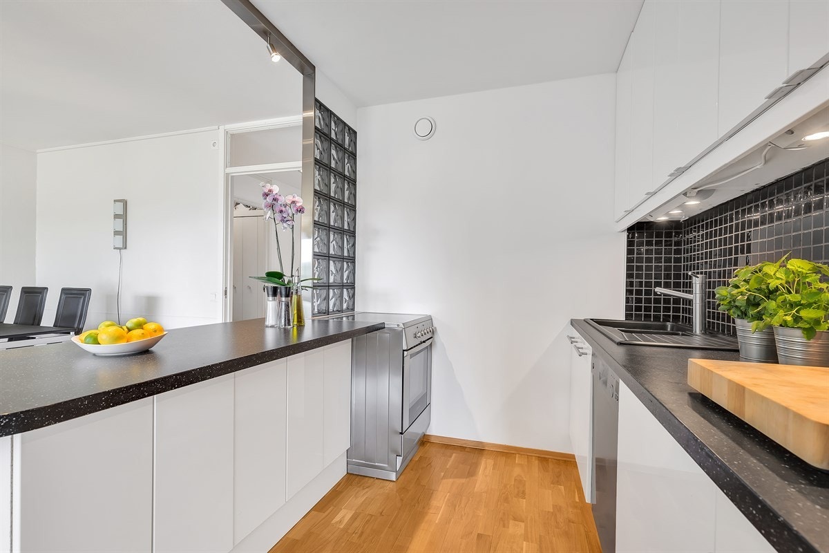 Kjøkkenet er fra 2006 med lyse fronter i høyglans, slitesterk laminatbenkeplate og flislagt vegg over benken Galleribilde