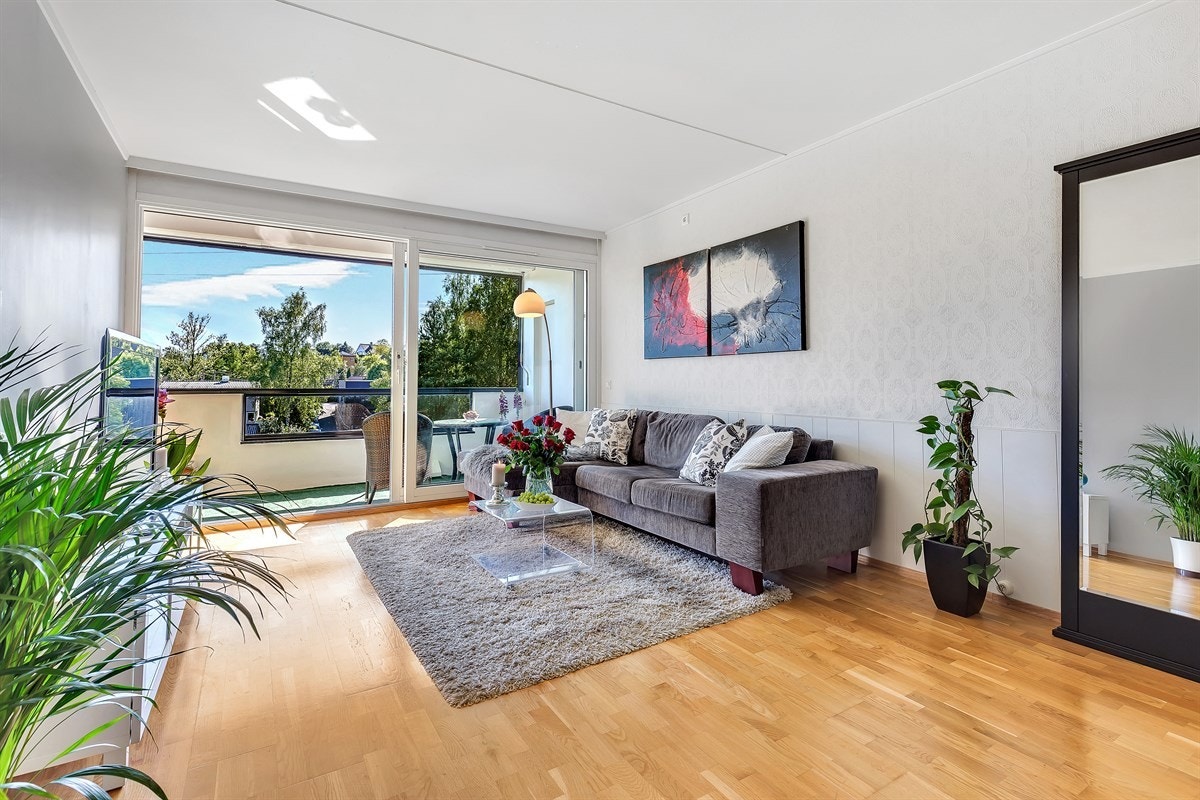 Eikeparketten strekker seg helt fra entrédøren til de sjenerøse vindusflatene, som gir oppholdsrommet rikelig med naturlig lys Galleribilde