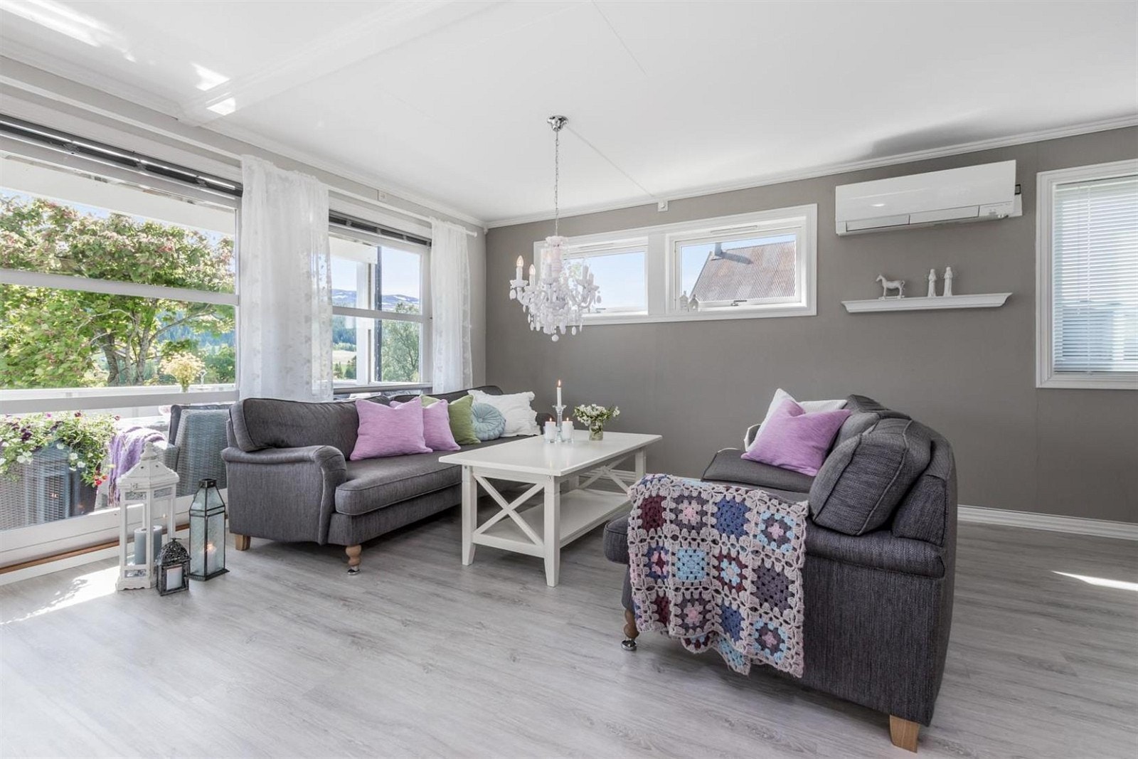 Stuen er pent innredet med flott gulv og moderne farger. Legg merke til vinduene som går fra tak til gulv mot hagen. Galleribilde