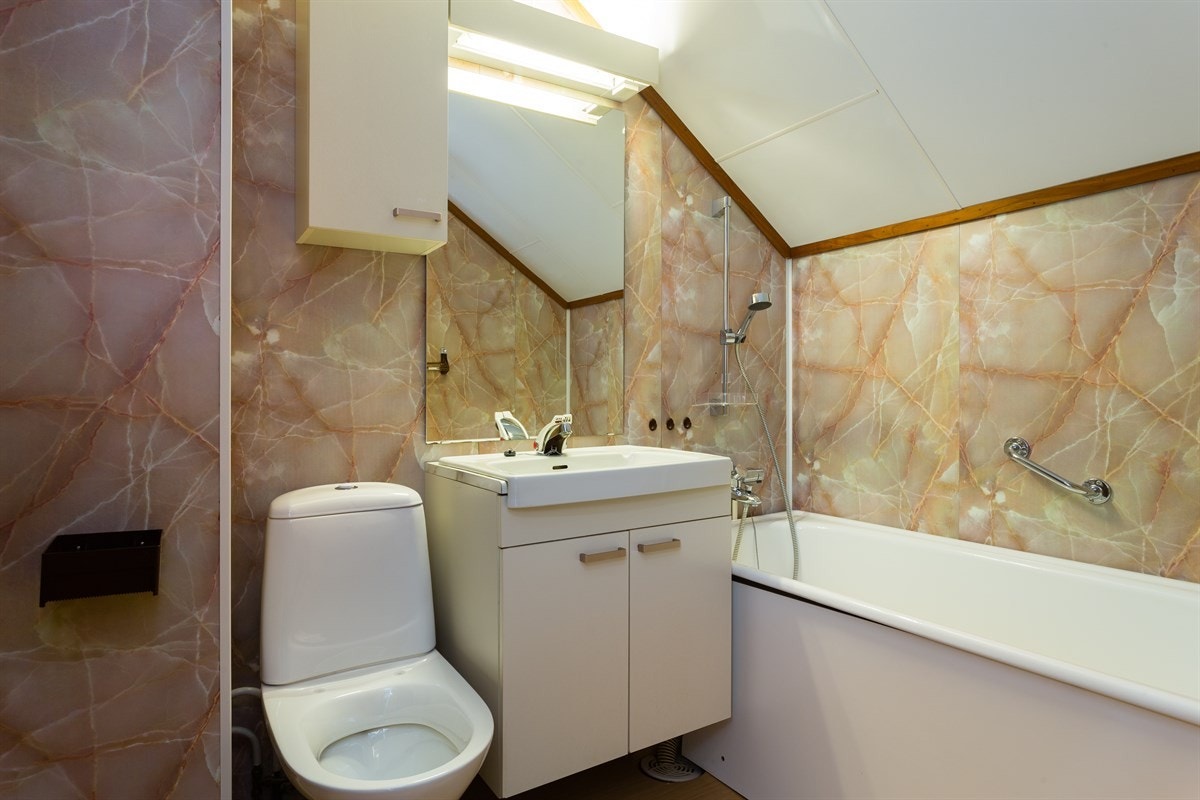 Baderommet er utstyrt med baderomsinnredning med heldekkende servant, dusjhjørne, toalett og badekar. Galleribilde