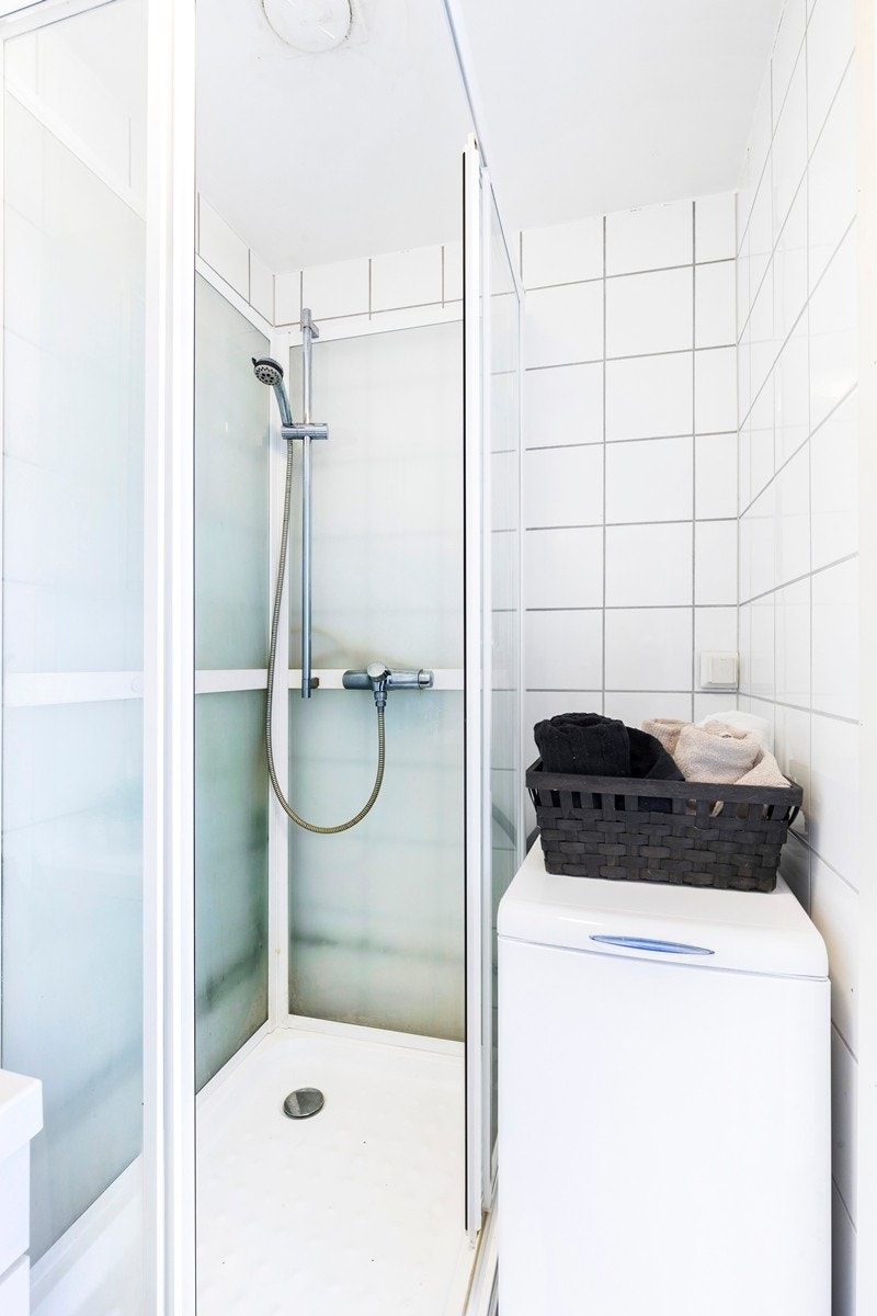 Badet er innredet med opplegg for vaskemaskin, frittstående toalett, dusjkabinett og servant med underskap Galleribilde