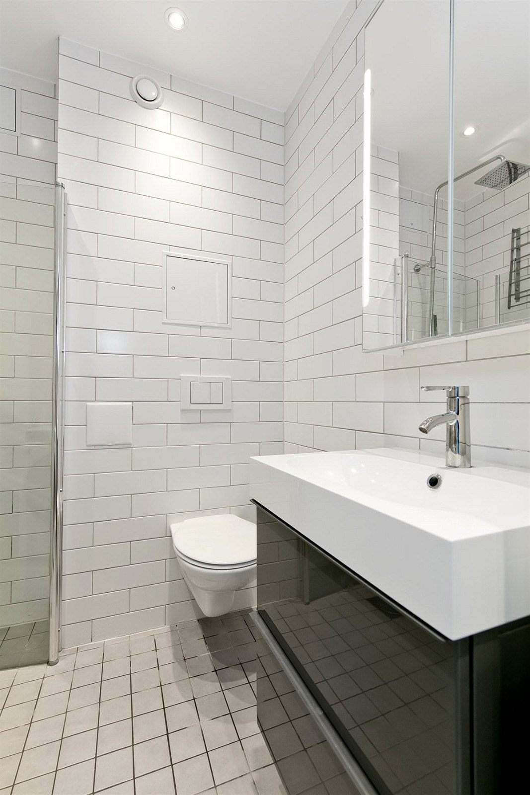 Badet har opplegg til vaskemaskin, dusjhjørne, vegghengt toalett og servant med underskap Galleribilde