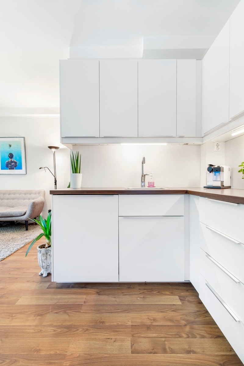 Kjøkkeninnredning med hvite slette fronter. Malte overflater og belysning over laminat benkeplate med nedfeldt oppvaskkum med 1 greps blandebatteri. Galleribilde