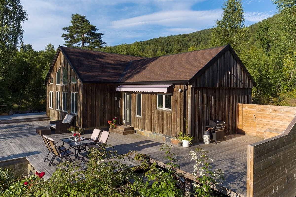 Terrassen har levegg, markise, og nydelige blomsterbed på nedsiden. Galleribilde