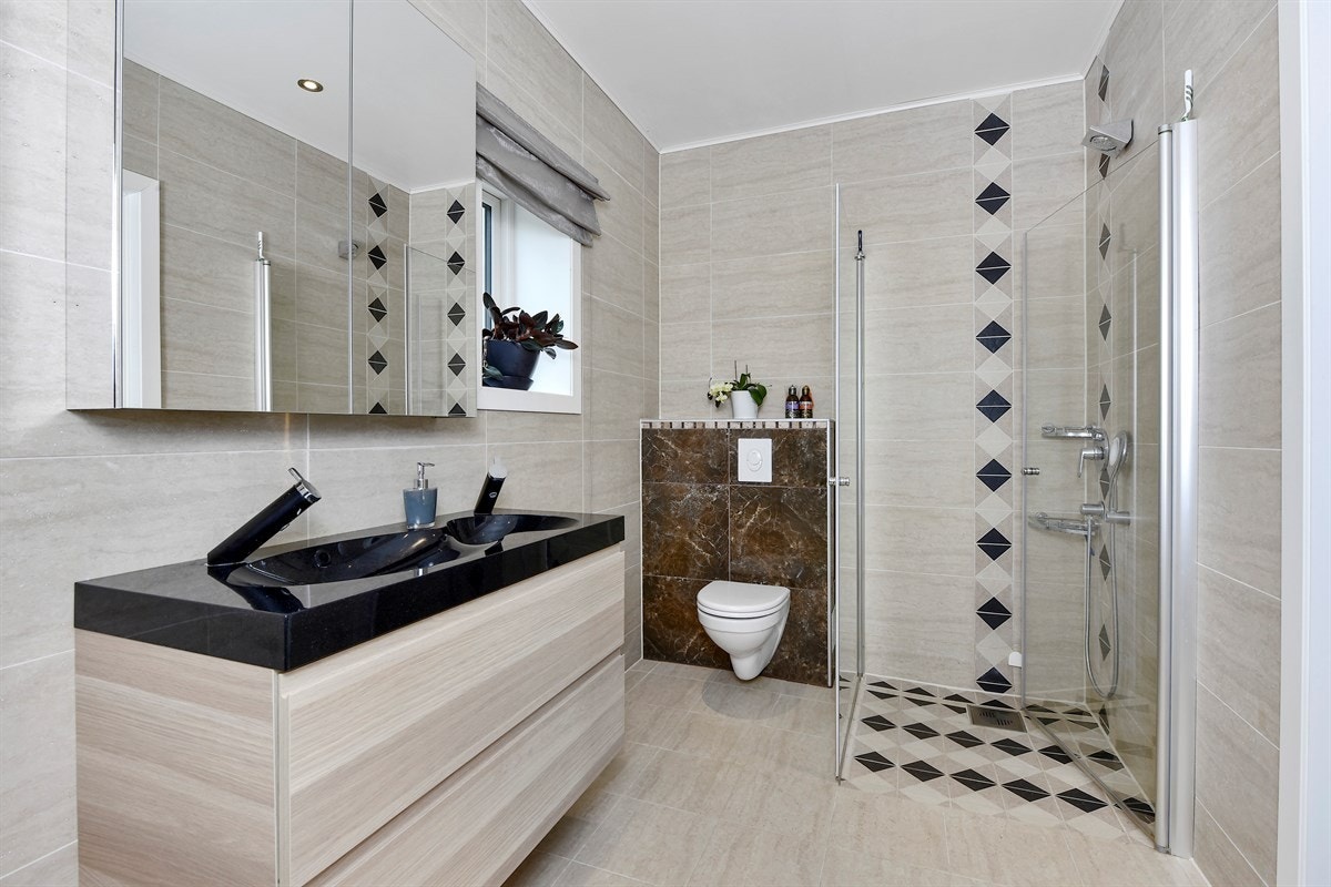 Boligen inneholder to delikate bad. Det første badet har sandfargede fliser på gulv og vegger, downlights og gulvvarme. Galleribilde