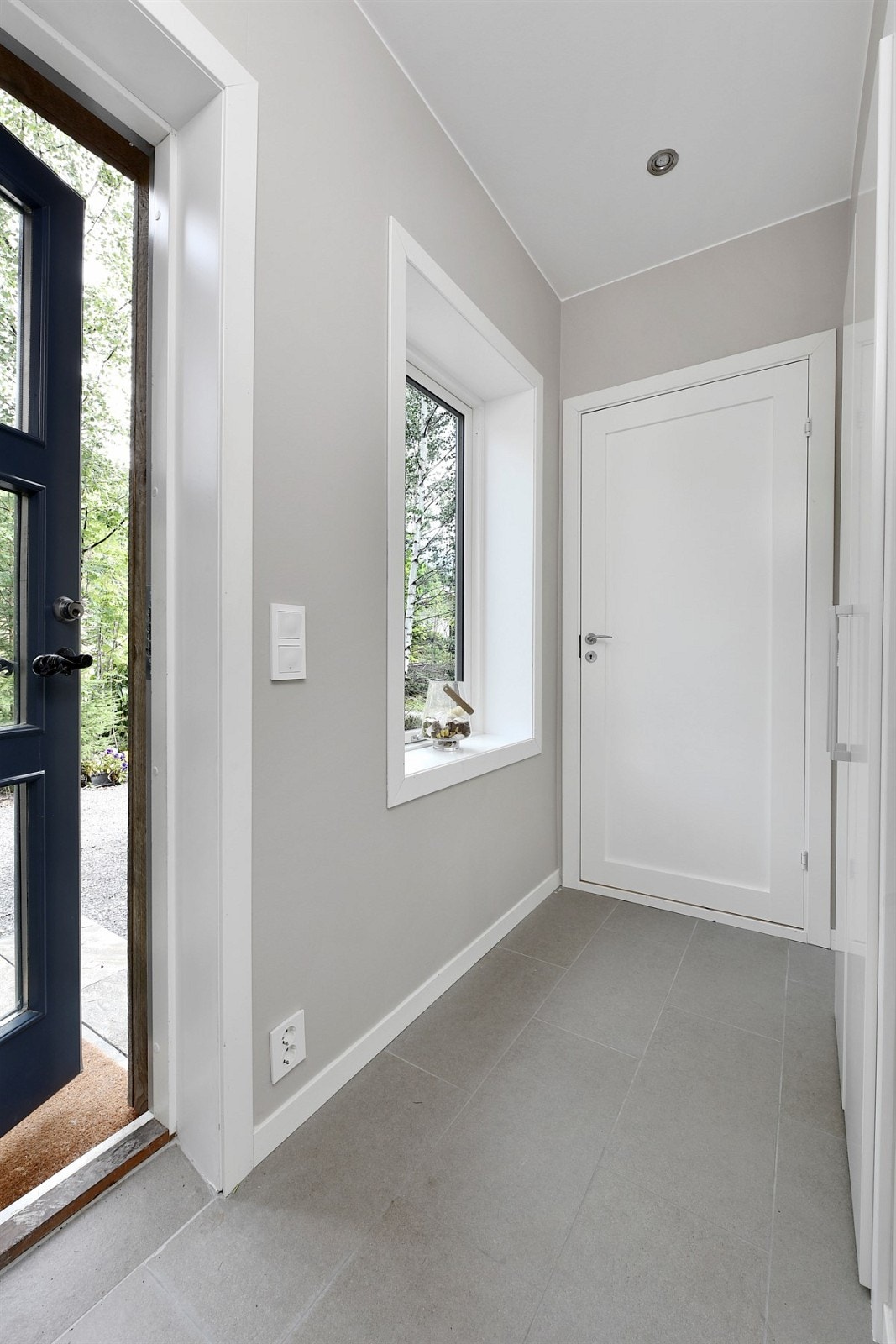 Entreen er innbydende med lyse fliser på gulv, malte veggflater og downlights i himling. Galleribilde