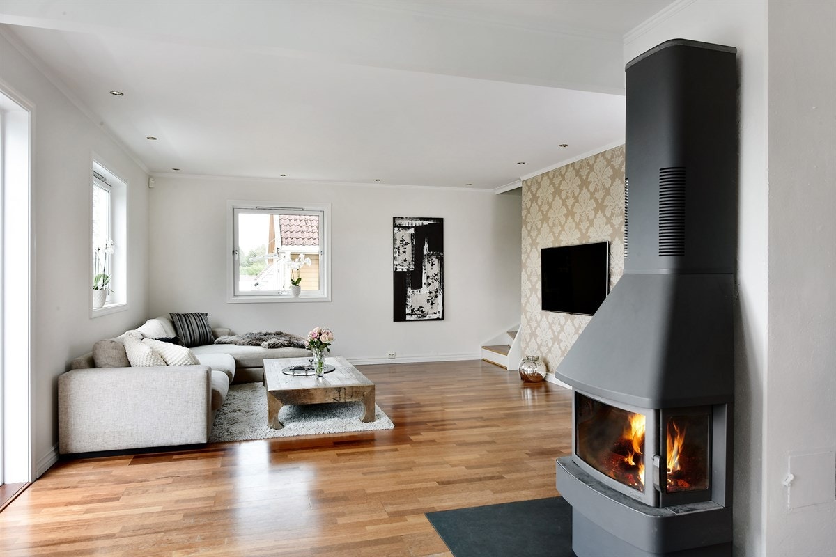 Sentralt i stuen er det en stilig peisovn med glassdør, noe som gir rommet en ekstra dimensjon av varme og hygge. Galleribilde