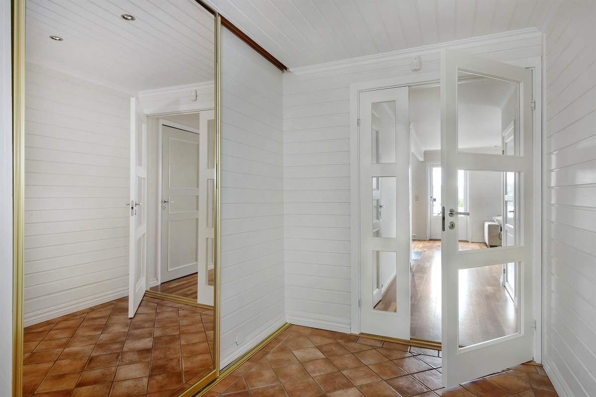Boligen har en lys og innbydende entré som gir et godt førsteinntrykk av tomannsboligen. Rommet har blant annet downlights, brune fliser på gulv med gulvvarme, åpen garderobeløsning, alarmpanel og stor skyvedørsgarderobe med speilfront. Galleribilde