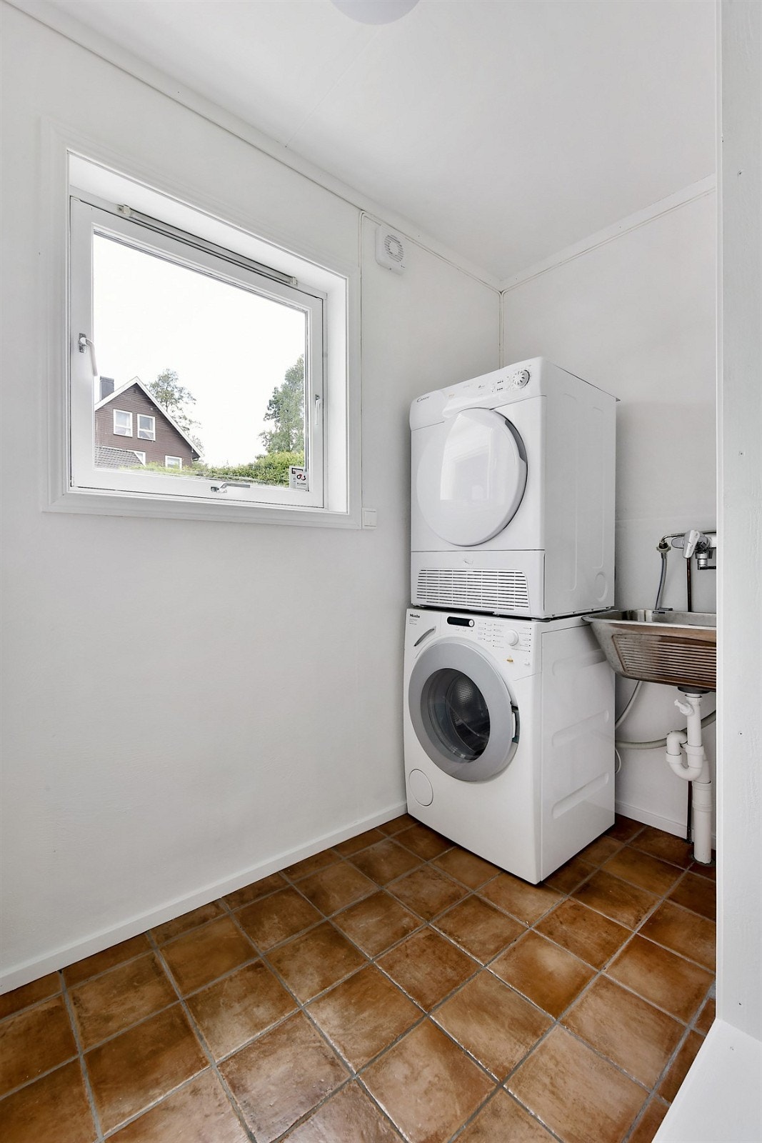 Vaskerommet er innredet med brune fliser på gulv og lysmalte vegger. Rommet har videre vaskekum, elektrisk avtrekksvifte, samt opplegg for vaskemaskin og tørketrommel. Galleribilde