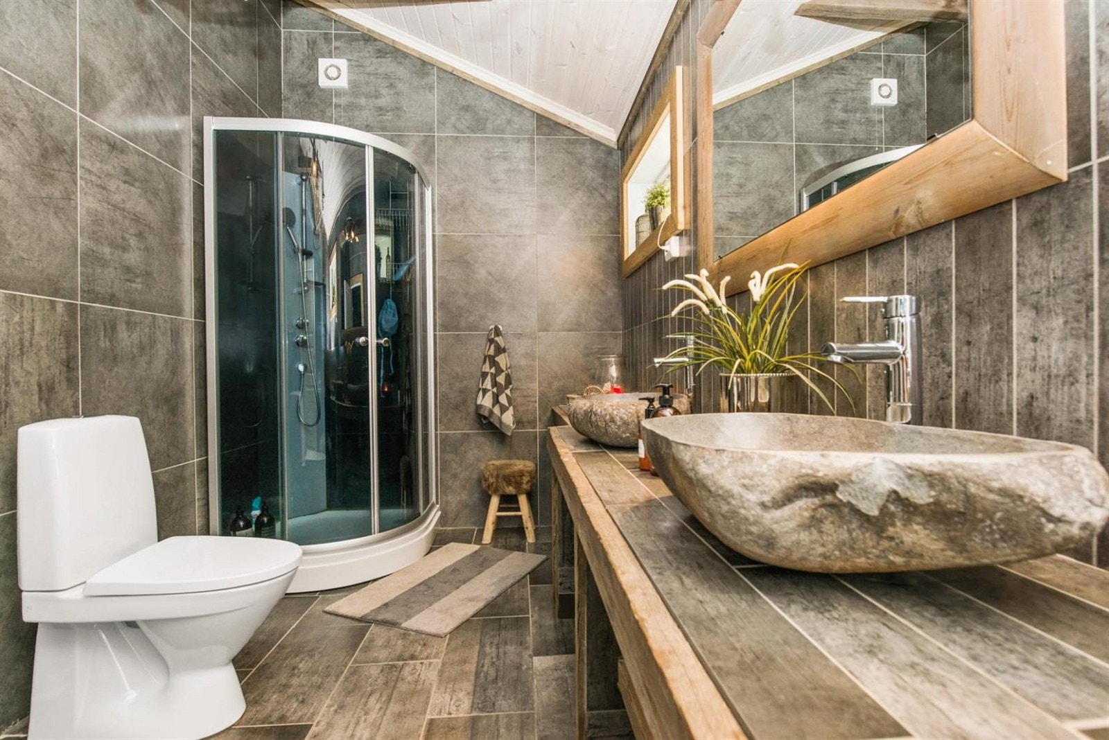 Eksklusivt, flislagt bad i 1.etg med åpen himling, håndlaget benk langs veggen og håndvasker laget av elvestein fra Indonesia. Galleribilde