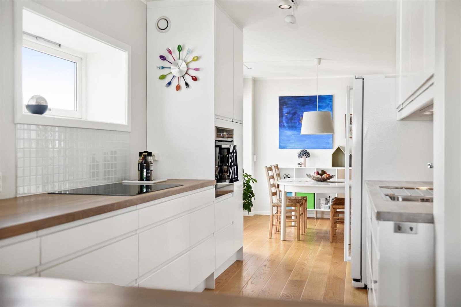 Pent og klassisk kjøkken fra Epoq i 2013 med innredning med glatte hvite fronter. Hvitoljede heltre eik benkeplater med nedfellt rustfri oppvaskum. Mosaikkfliser over benker. Galleribilde