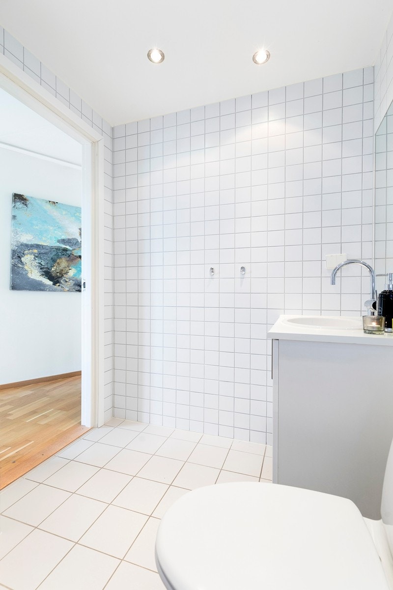 Lyst og pent flislagt bad med varmekabler i gulv, downlights belysning i tak og opplegg for vaskemaskin. Galleribilde