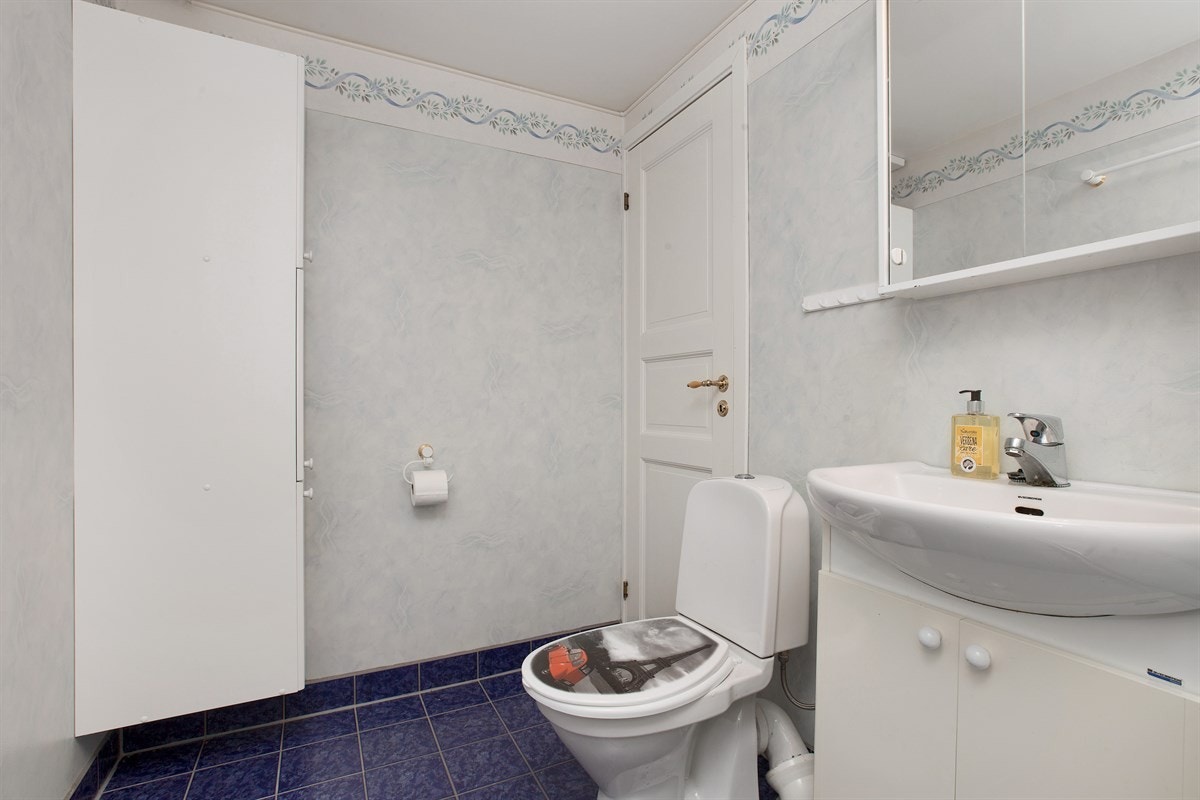 Badet i første etasje er funksjonelt, og har blå fliser på gulv, baderomstapet og gulvvarme. Galleribilde