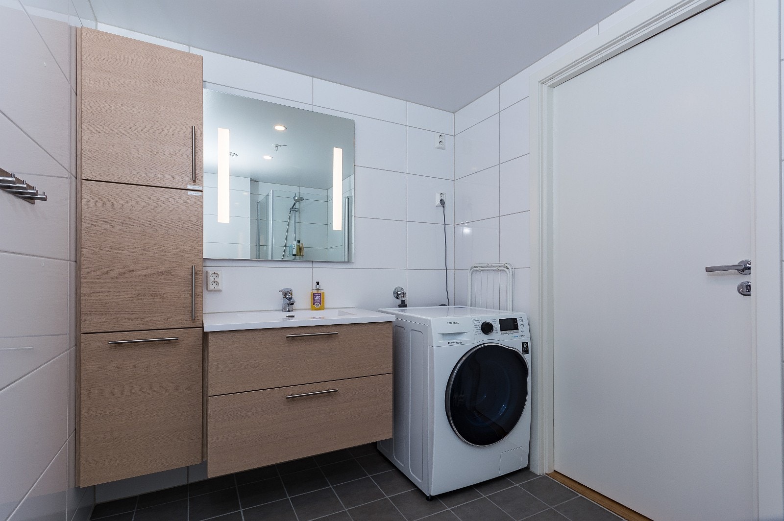 Bad med dusj og vask/tørk-maskin. Ekstra skap montert over vaskemaskin etter at bildet ble tatt. Galleribilde