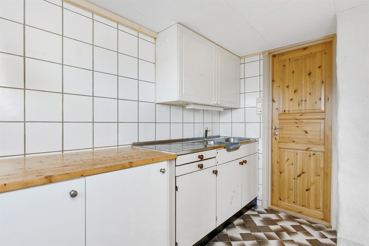 Det andre kjøkkenet ligger i underetasjen og har en eldre innredning med hvite, glatte fronter. Galleribilde