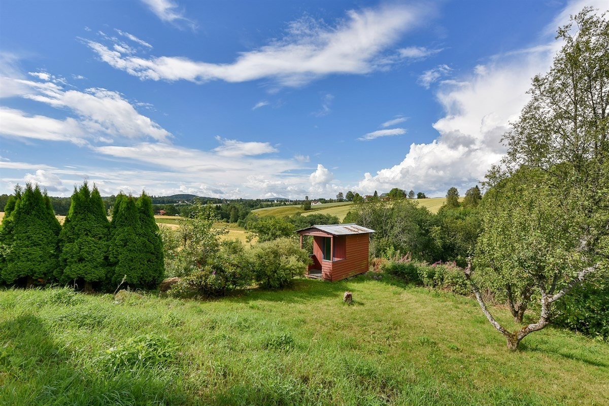 Hagen har ellers plen, frodig beplantning, prydbusker og flaggstang Galleribilde
