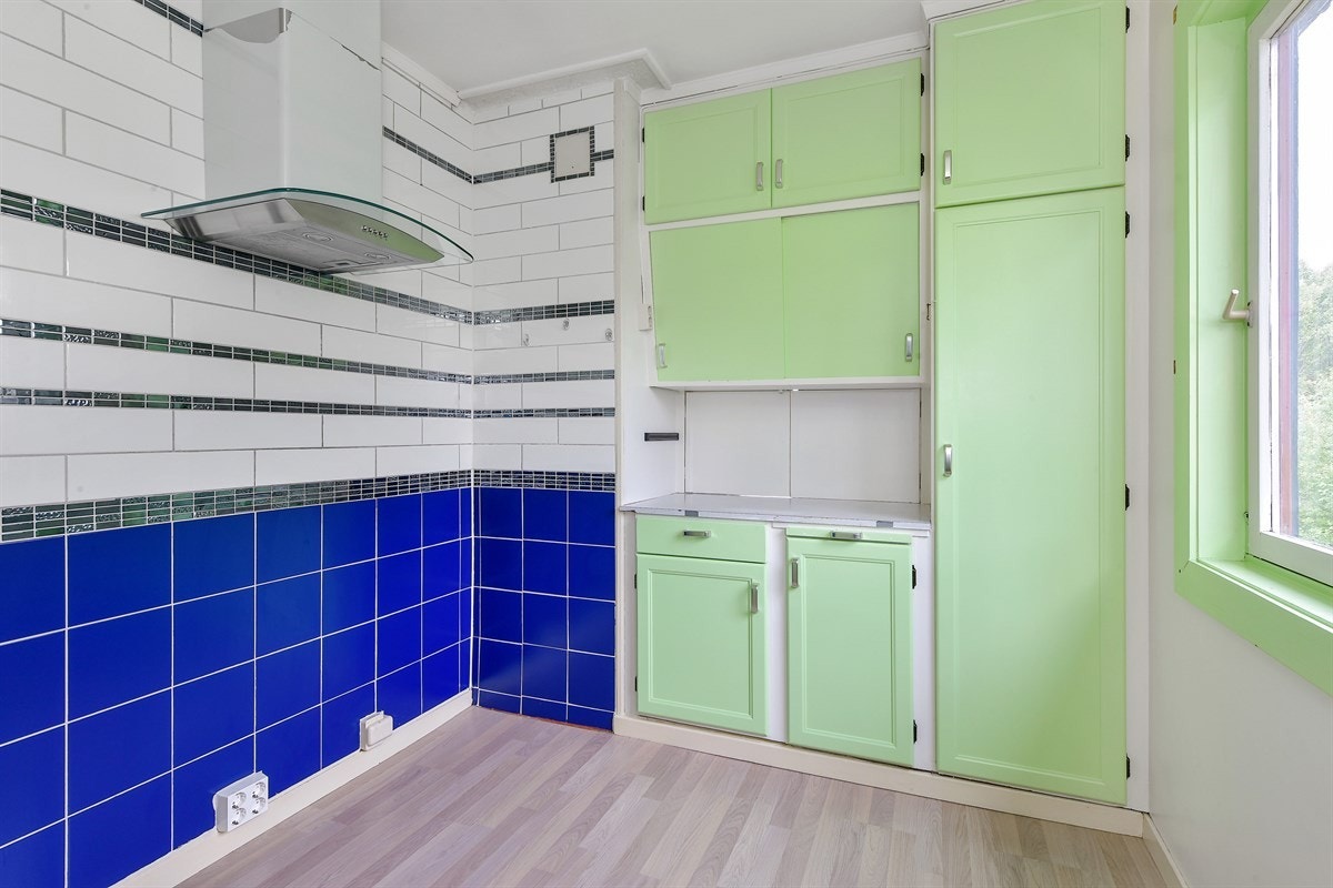 Det er lagt fliser langs en hel vegg, og her det avsatt plass for komfyr og montert ventilator med hette i glass. Galleribilde