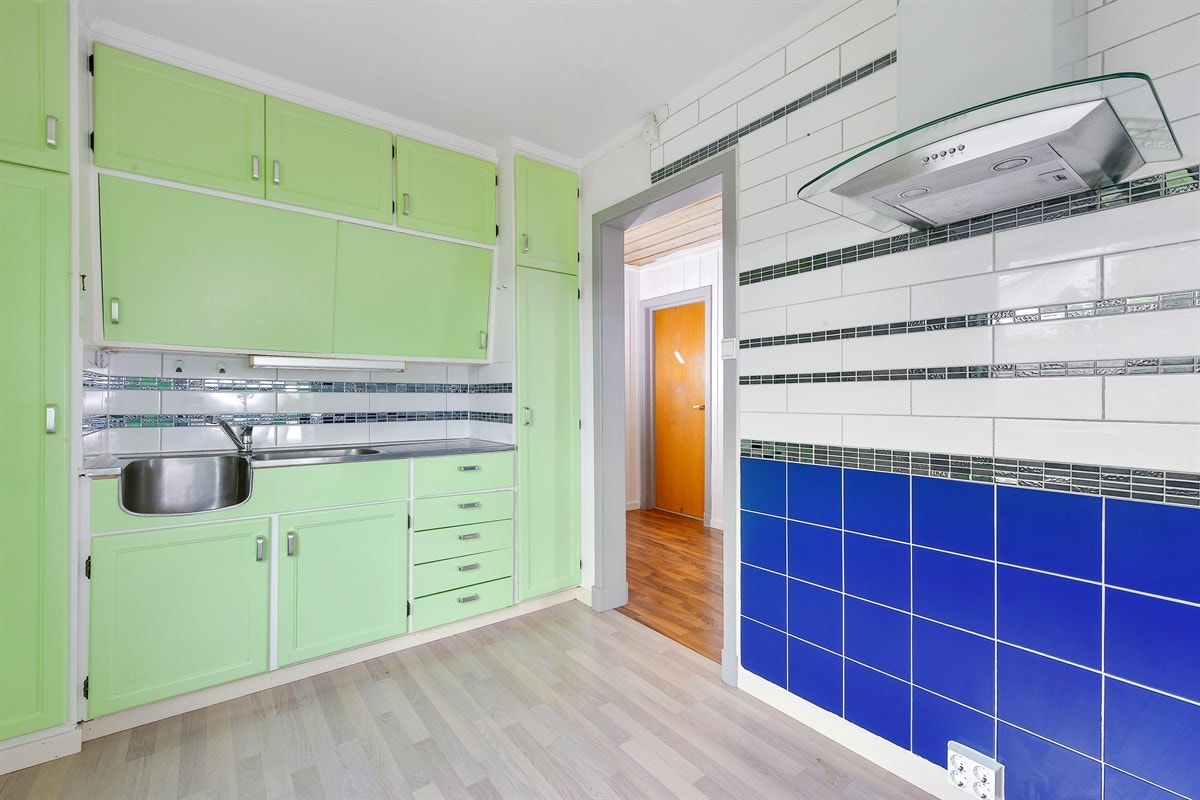 Kjøkkene besitter en benkeplate i lys laminat, heldekkende vaskekum og sjarmerende, skråstilte overskap. Galleribilde