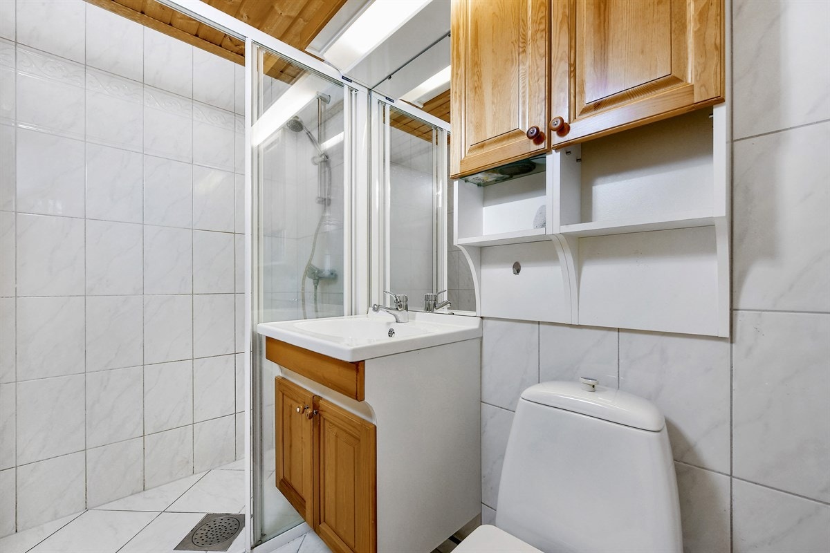 Badet i første etasje er også flislagt og har varmekabler i gulv. Det er utstyrt med et frittstående toalett og et stort dusjhjørne med skyvedører. Galleribilde